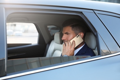 Handsome man talking on phone in modern car