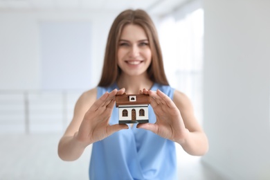 Beautiful real estate agent with house model indoors
