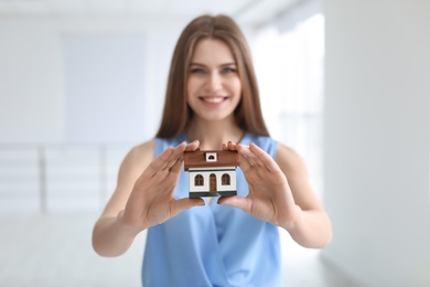 Photo of Beautiful real estate agent with house model indoors