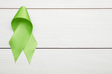 World Mental Health Day. Green ribbon on white wooden background, top view with space for text