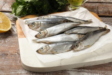 Photo of Fresh raw sprats on wooden table, closeup