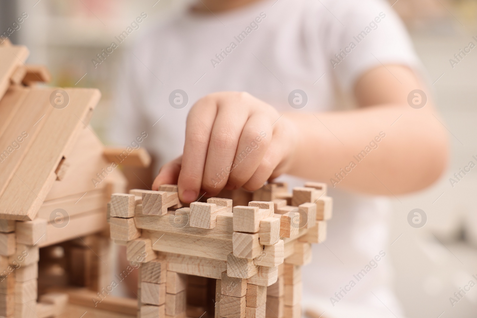 Photo of Little boy playing with wooden construction set in room, closeup. Child's toy