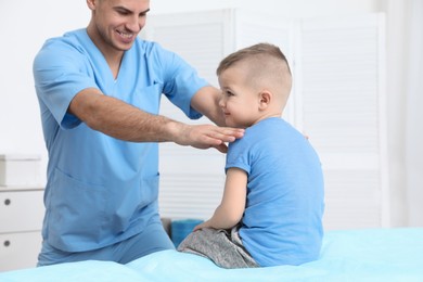 Photo of Orthopedist examining child in clinic. Scoliosis treatment