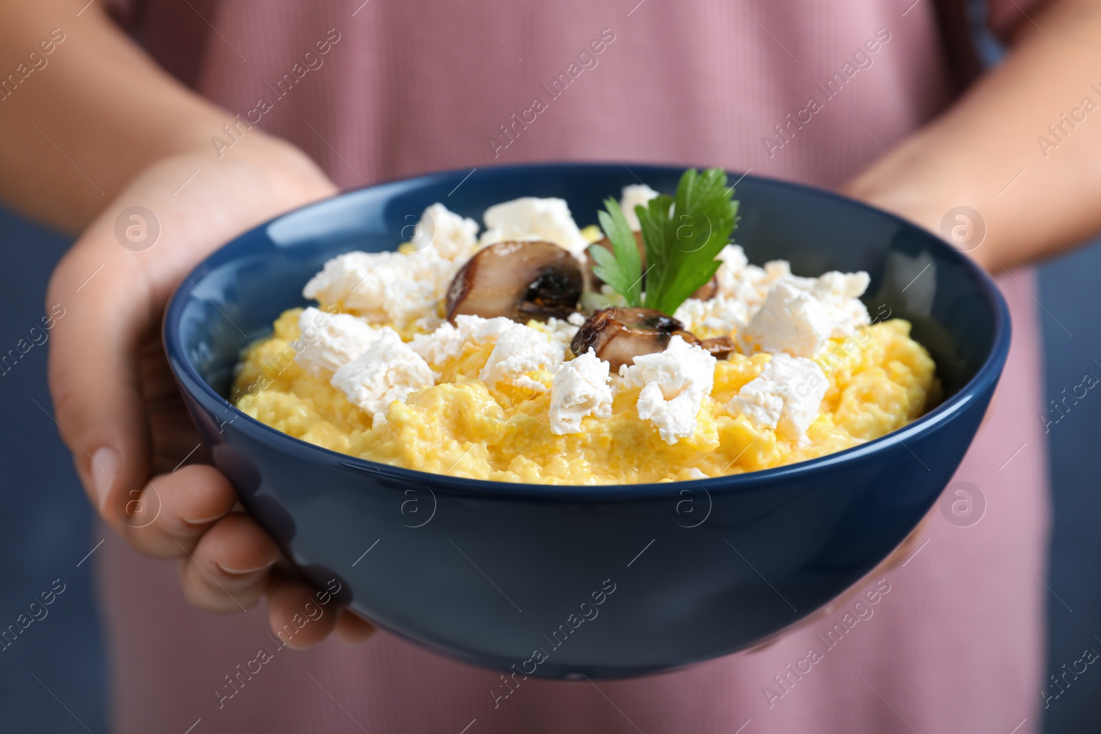 Photo of Woman holding bowl of banosh with brynza and mushrooms, closeup. Traditional Ukrainian dish