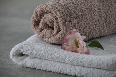 Photo of Soft towels with flower on grey table, closeup