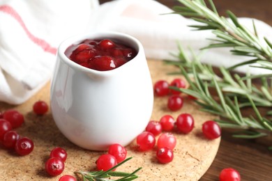 Photo of Cranberry sauce, fresh berries and rosemary on table, closeup