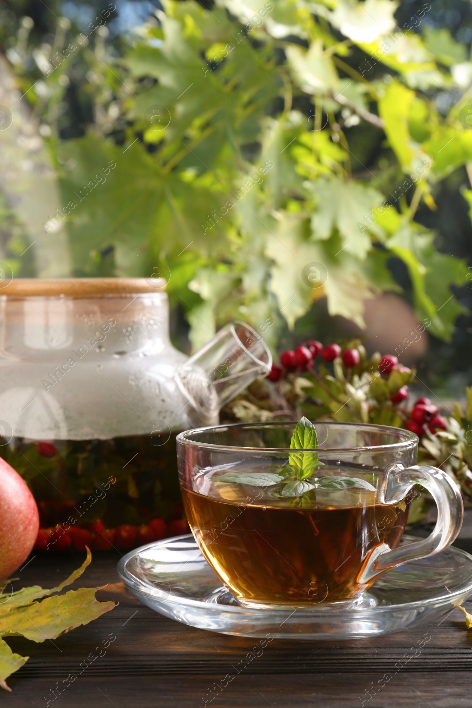 Photo of Hot tea, apples and dry leaves on wooden windowsill. Autumn atmosphere