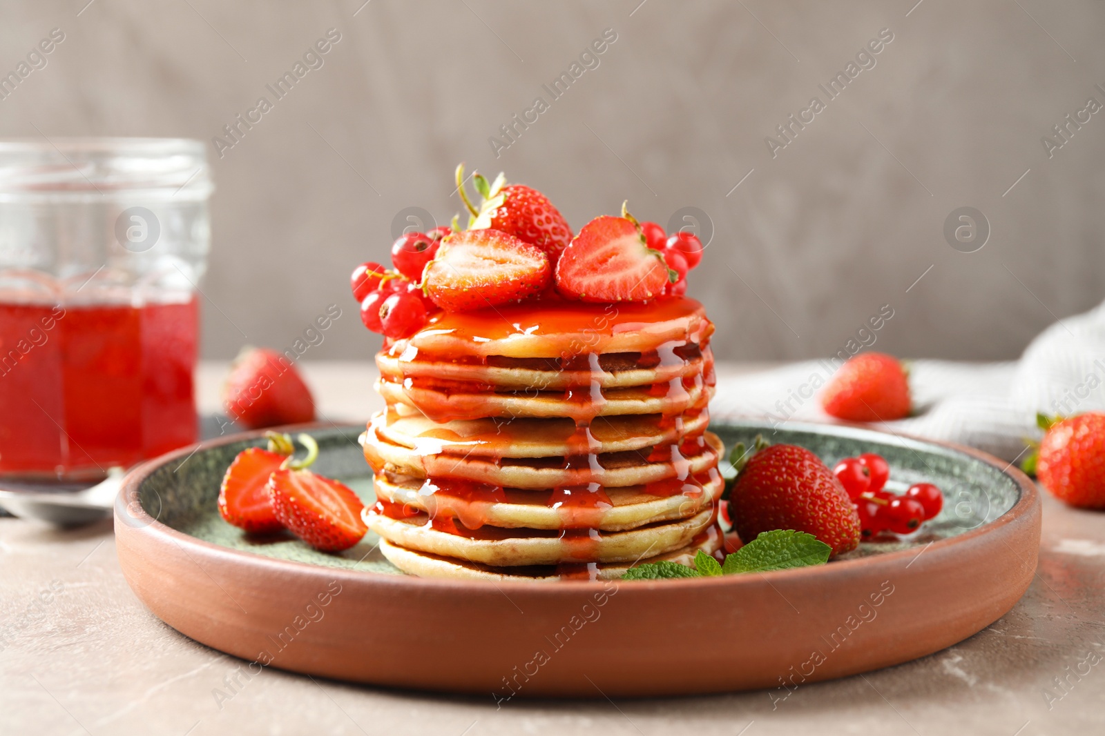 Photo of Delicious pancakes with fresh berries and syrup on beige marble table