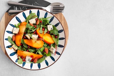 Photo of Tasty salad with persimmon, blue cheese, pomegranate and almonds served on white table, top view. Space for text