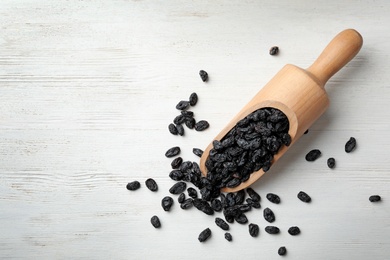 Photo of Scoop of raisins on wooden background, top view with space for text. Dried fruit as healthy snack