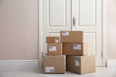 Photo of Stacked parcels near door on floor, space for text. Delivery service