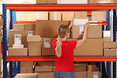 Photo of Post office worker taking parcel from rack indoors, back view