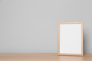 Empty square frame on wooden table, space for text