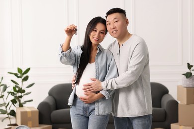 Photo of Pregnant woman and her husband with key in their new apartment