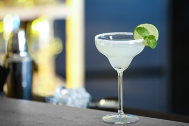 Photo of Fresh alcoholic cocktail with lime and mint on bar counter, space for text