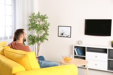 Young couple watching TV on sofa at home