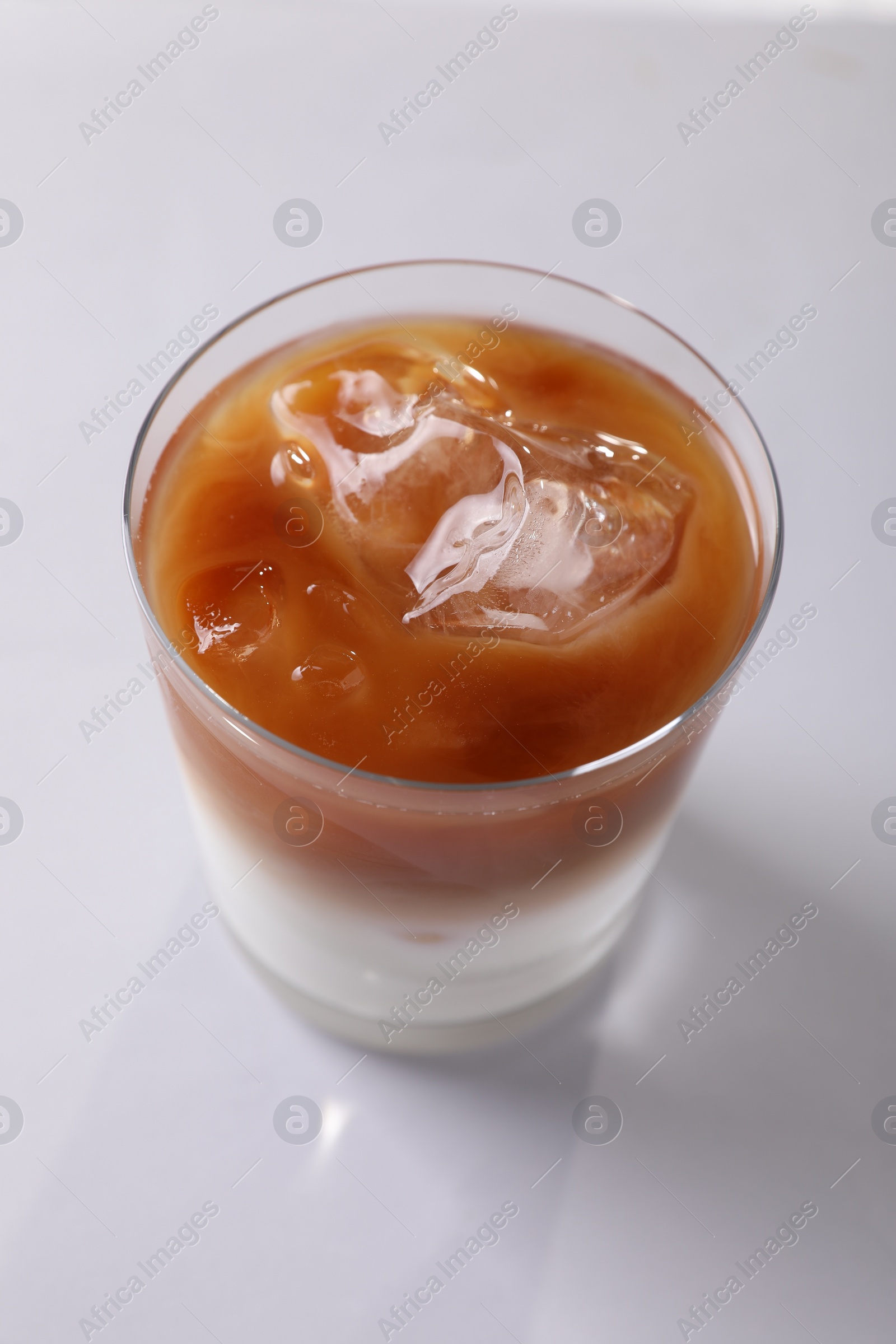 Photo of Glass of iced coffee on white table, closeup