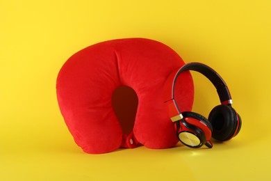 Photo of Red travel pillow and headphones on yellow background