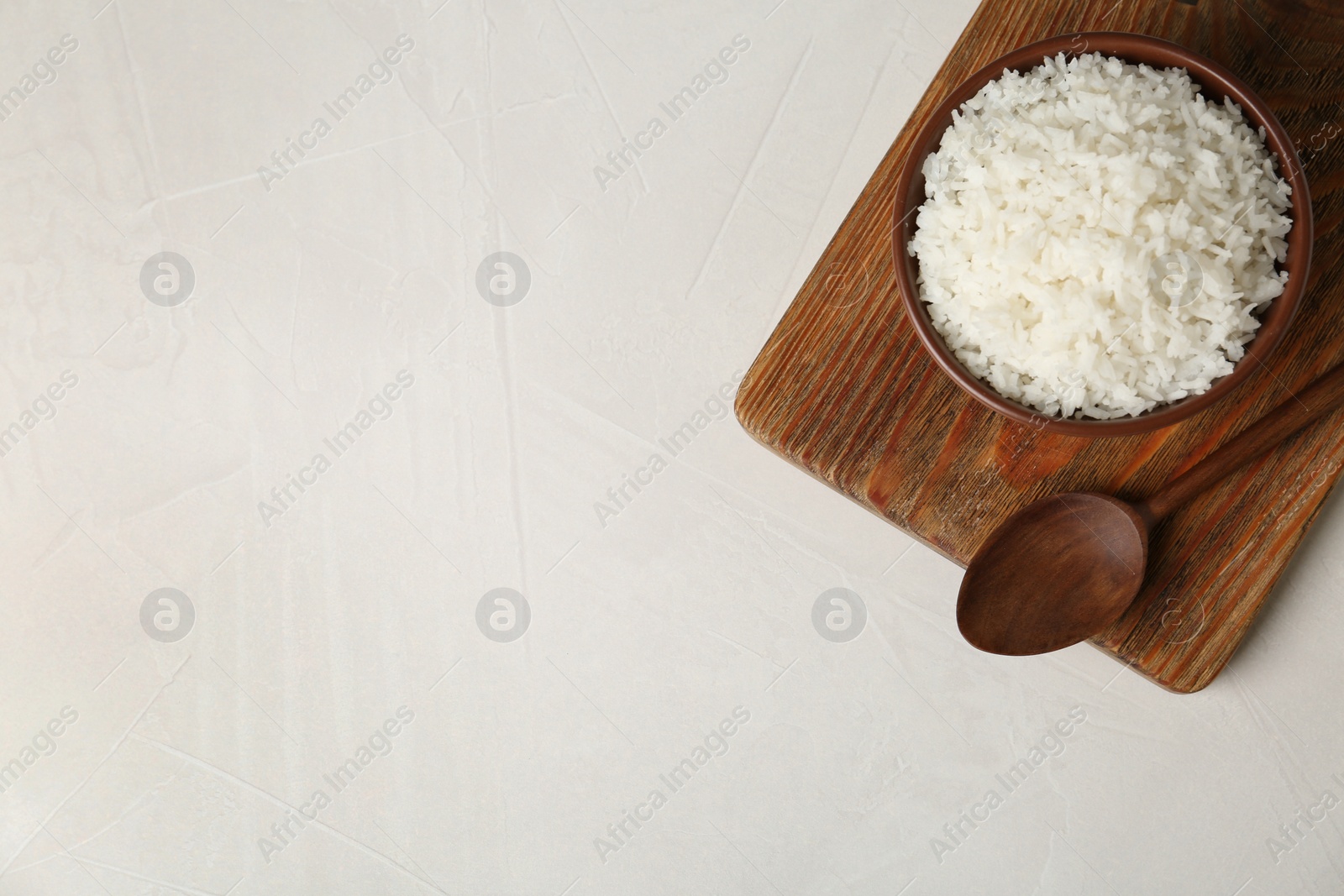 Photo of Bowl of boiled rice served on light background, top view with space for text