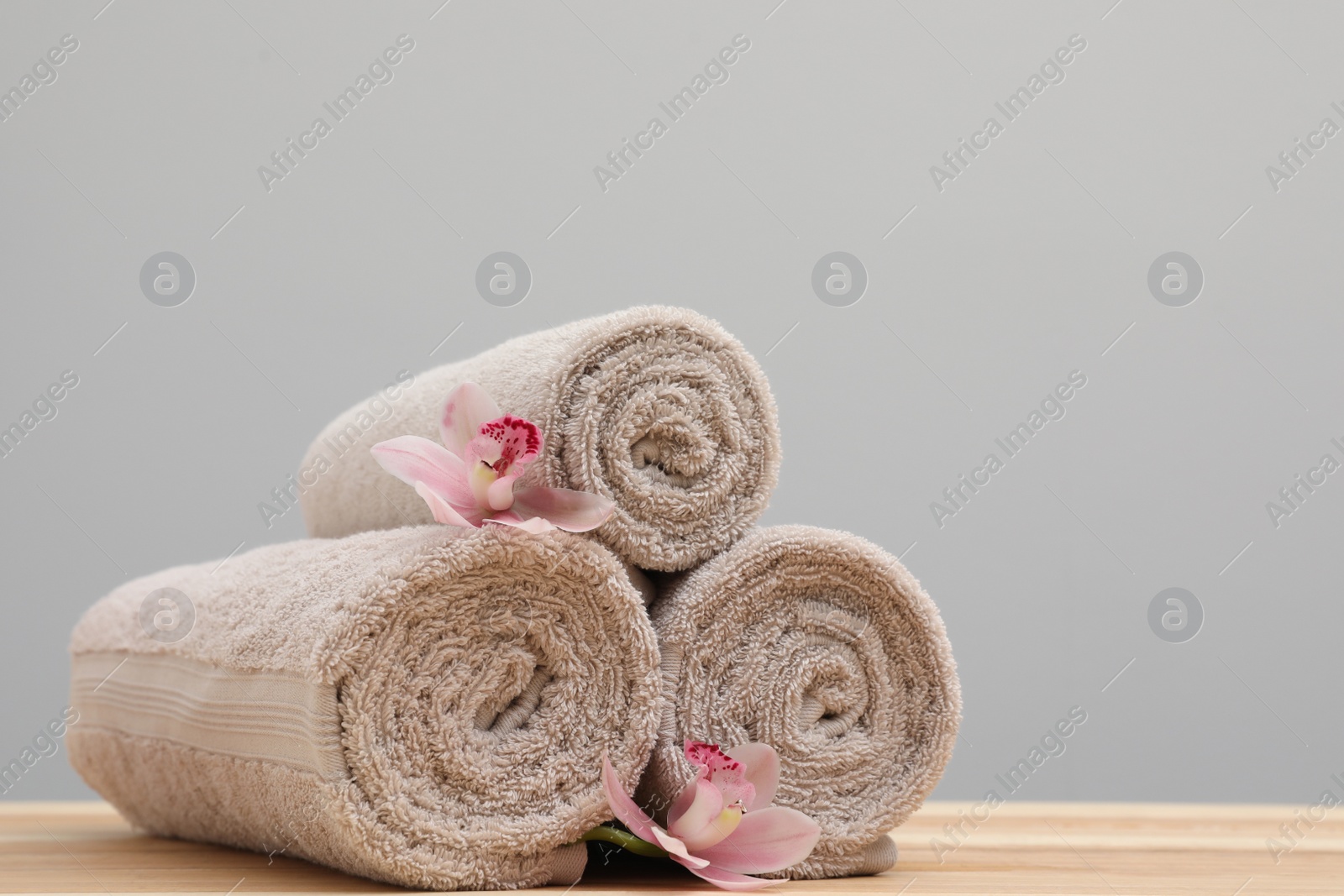 Photo of Stack of rolled towels and flowers on table. Space for text