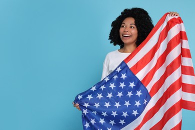 4th of July - Independence Day of USA. Happy woman with American flag on light blue background, space for text