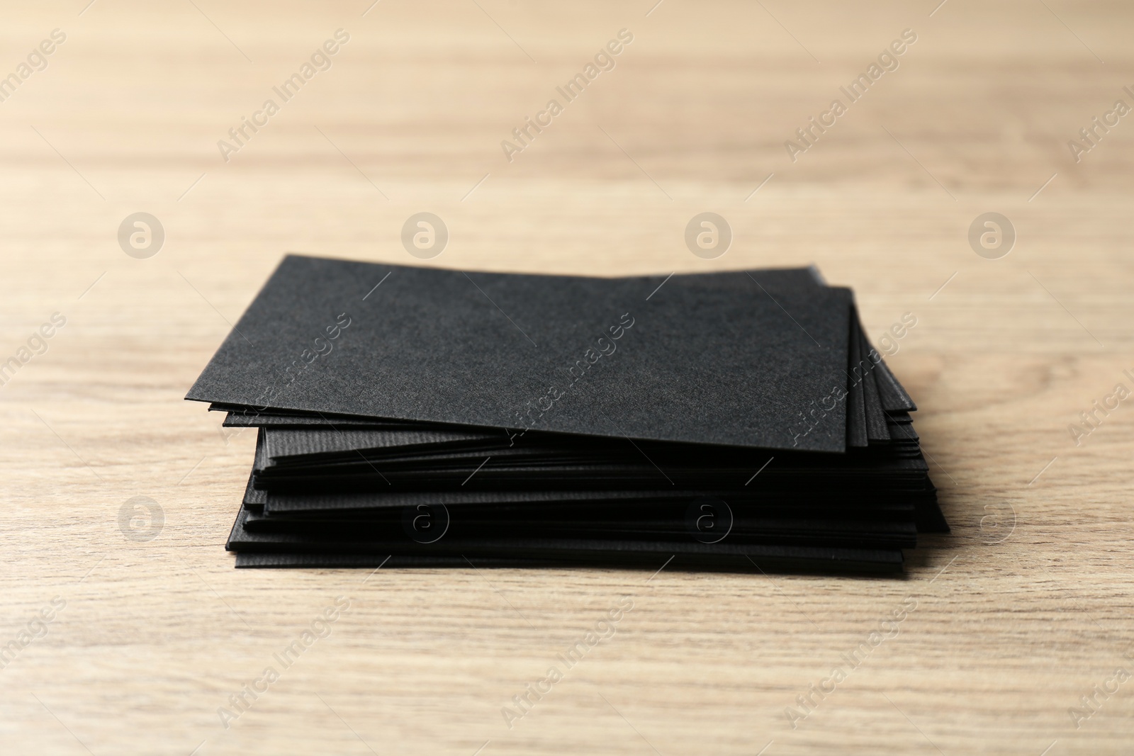 Photo of Blank black business cards on wooden table, closeup. Mockup for design