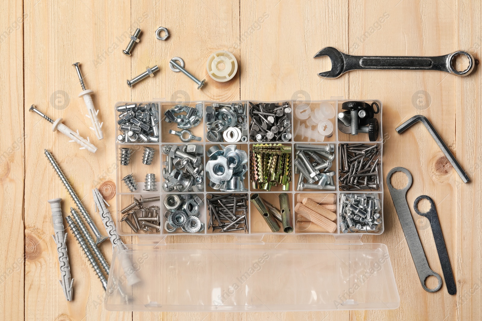 Photo of Organizer with many different fasteners and wrenches on wooden table, flat lay