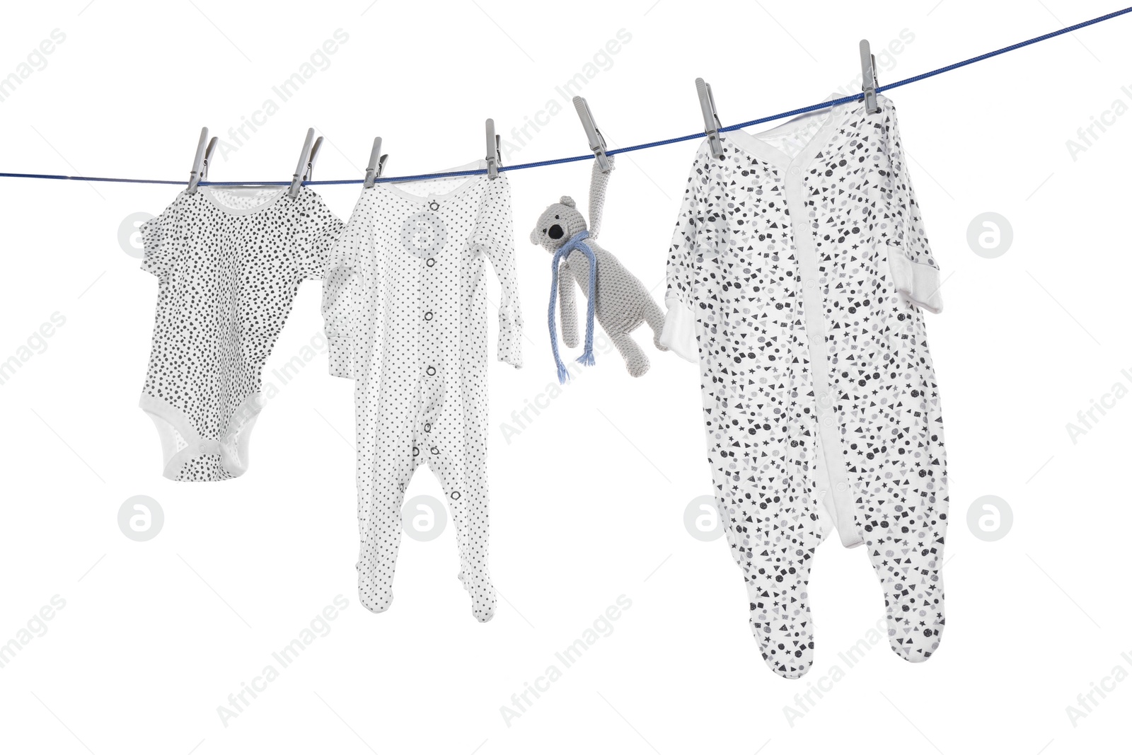 Photo of Different baby clothes and toy drying on laundry line against white background