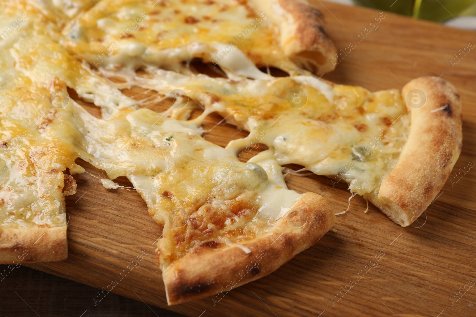 Photo of Delicious cut cheese pizza on wooden board, closeup