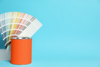 Photo of Can of orange paint and color palette samples on turquoise background. Space for text