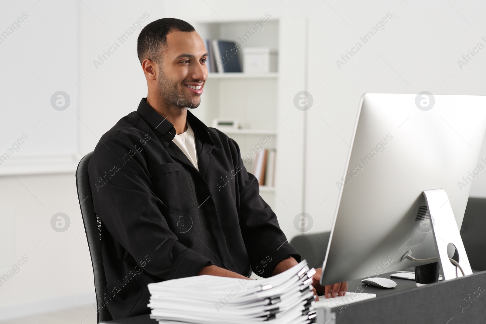 Photo of Happy man working with documents at grey table in office