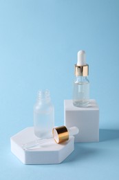 Presentation of bottles with cosmetic serums on light blue background