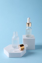 Photo of Presentation of bottles with cosmetic serums on light blue background