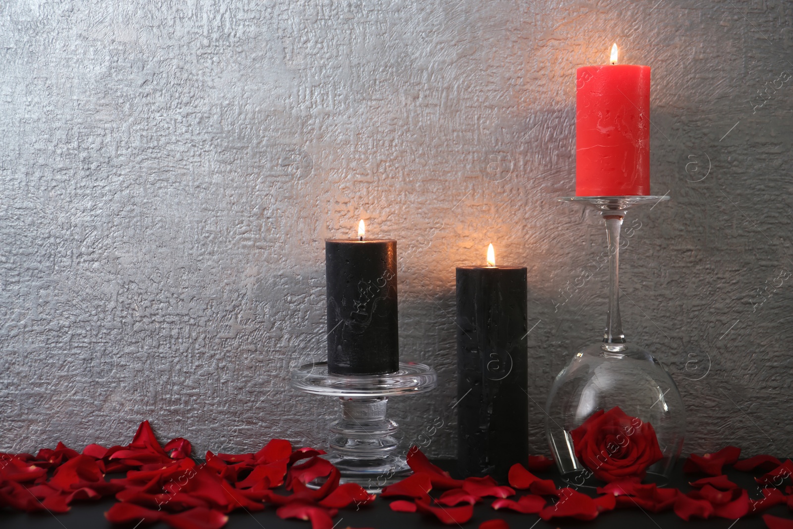 Photo of Candles with floral decor on table against color background