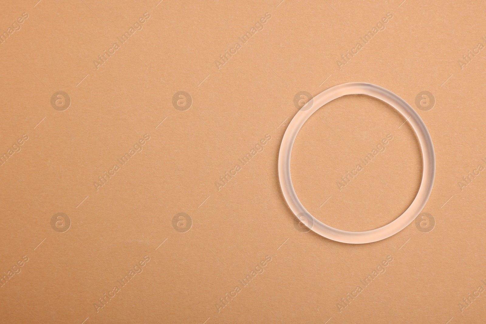 Photo of Diaphragm vaginal contraceptive ring on beige background, top view. Space for text