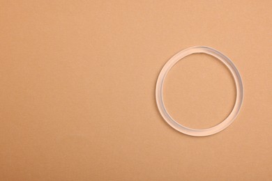 Photo of Diaphragm vaginal contraceptive ring on beige background, top view. Space for text