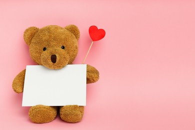 Photo of Cute teddy bear with red heart and blank card on pink background, space for text. Valentine's day celebration