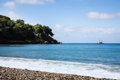 Beautiful sea beach near rocky hill with forest on sunny summer day