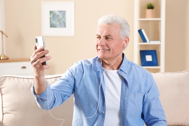 Photo of Mature man using video chat on mobile phone at home