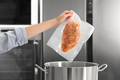 Photo of Woman putting vacuum packed meat into pot in kitchen, closeup