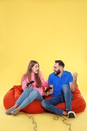 Emotional couple playing video games with controllers on color background. Space for text