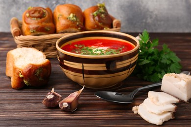 Photo of Delicious borsch served with pampushky and salo on wooden table. Traditional Ukrainian cuisine