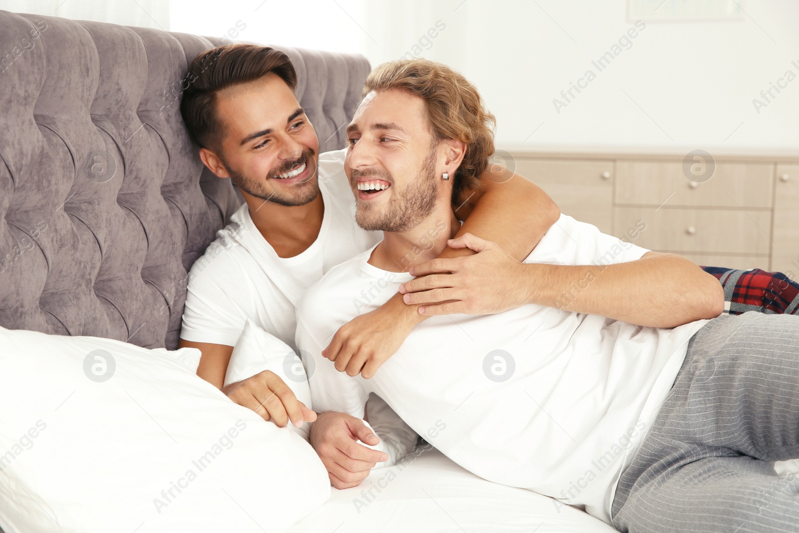 Photo of Happy gay couple on bed at home