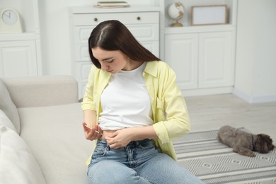 Diabetes. Woman making insulin injection into her belly on sofa at home