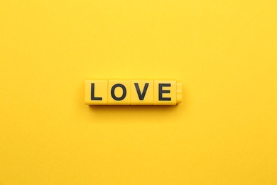 Cubes with word LOVE on yellow background, top view