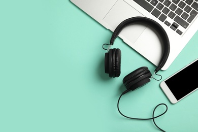 Modern headphones, phone and laptop on color background, flat lay. Space for text