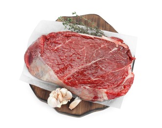 Photo of Wooden board with piece of raw meat, garlic and thyme isolated on white, top view