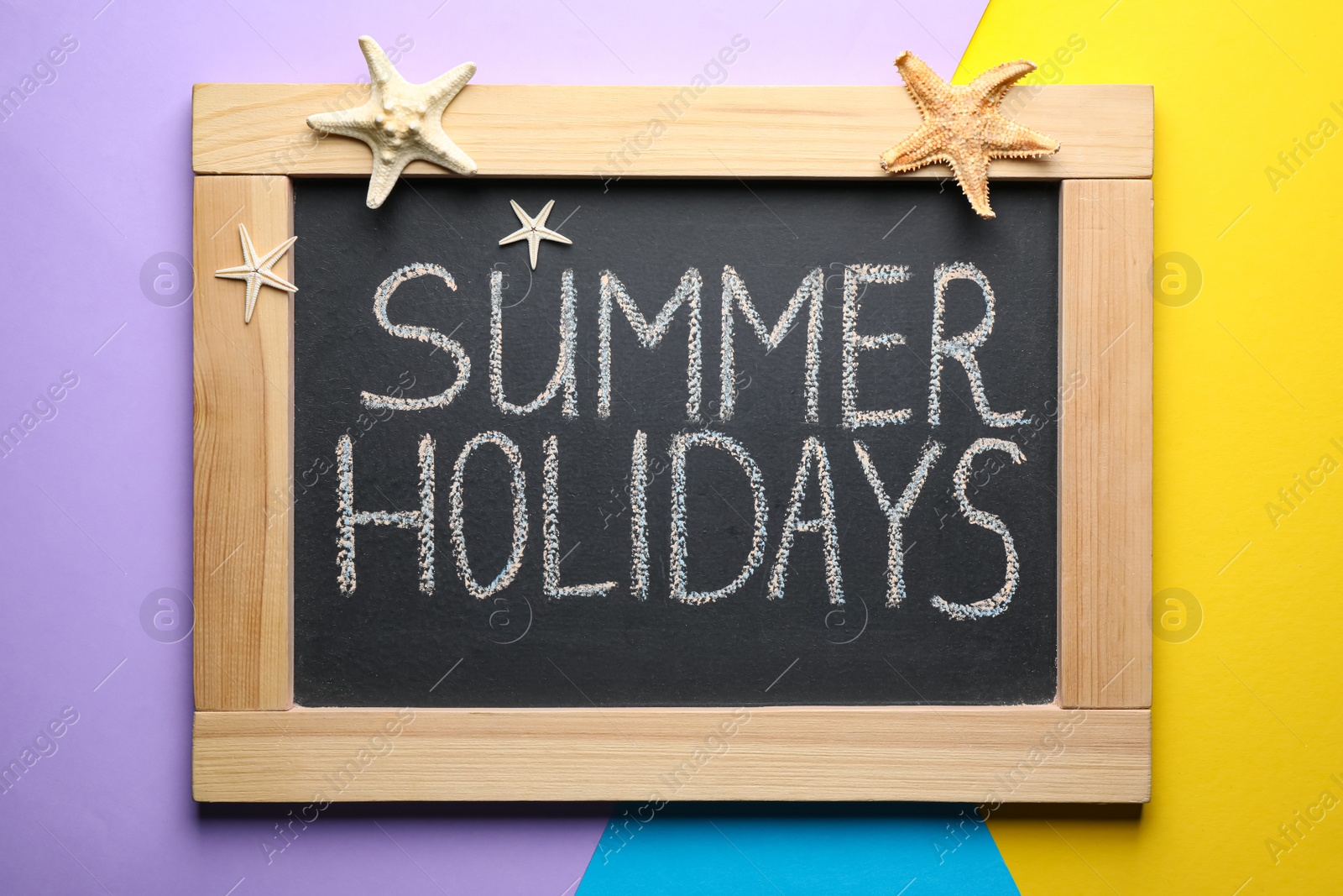 Photo of Chalkboard with phrase SUMMER HOLIDAYS on color background, top view. School's out