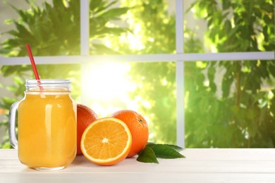 Fresh orange juice on wooden table near window. Space for text