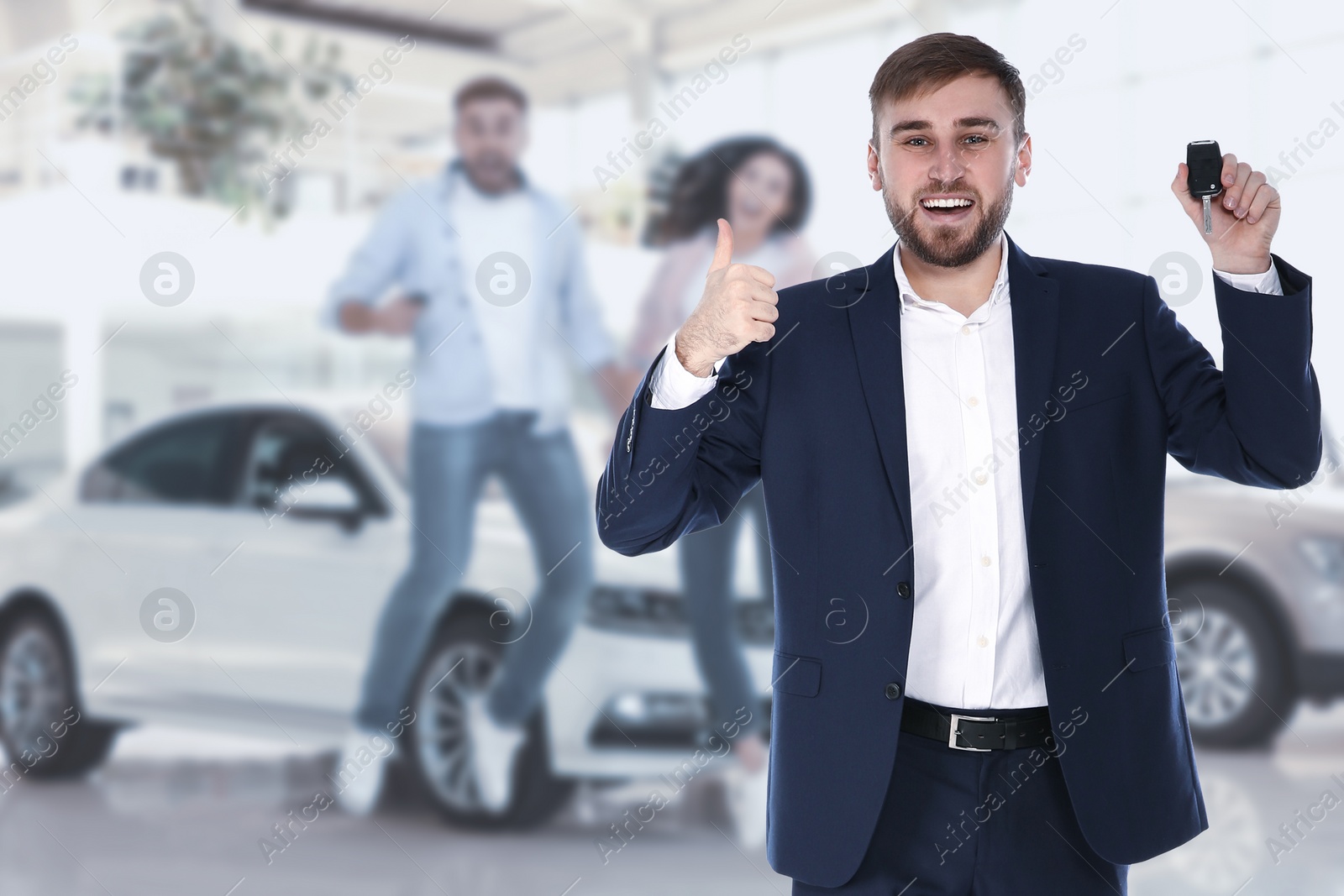 Image of Happy salesman with key in car salon